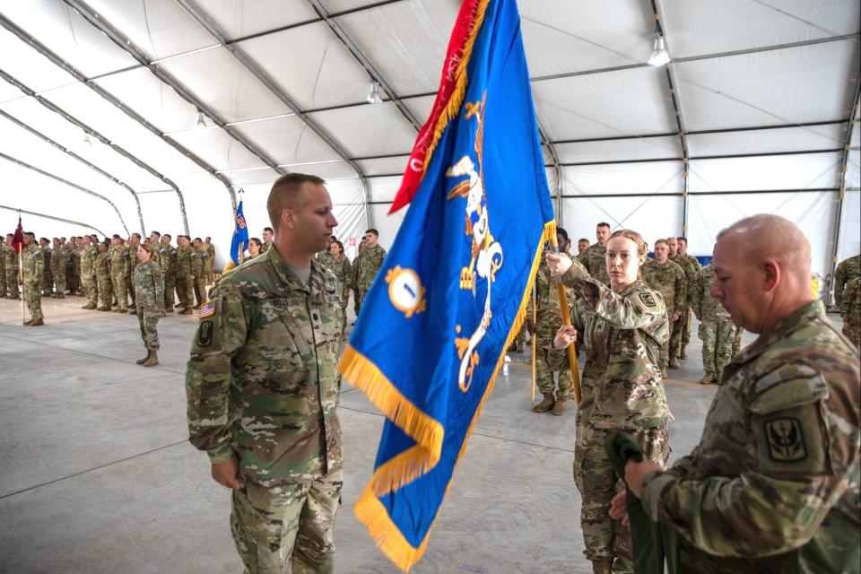 Sgt. Kimberly Sheridan, religious affairs specialist, serves as the battalion guidon bearer as Lt. Col. Jeffrey A. Sills, left, commander of the 1st Battalion, 126th Aviation Regiment, Rhode Island Army National Guard, and Command Sgt. Maj. Jodie M. Dove unfurl the unit colors during a transfer of authority ceremony at Camp Bondsteel, Kosovo, in June.