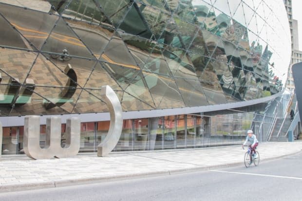 A cyclist rides past the dormant Shaw Centre in April. Workers who were laid off during the pandemic are speaking out, saying they feel abandoned. (Stu Mills/CBC - image credit)