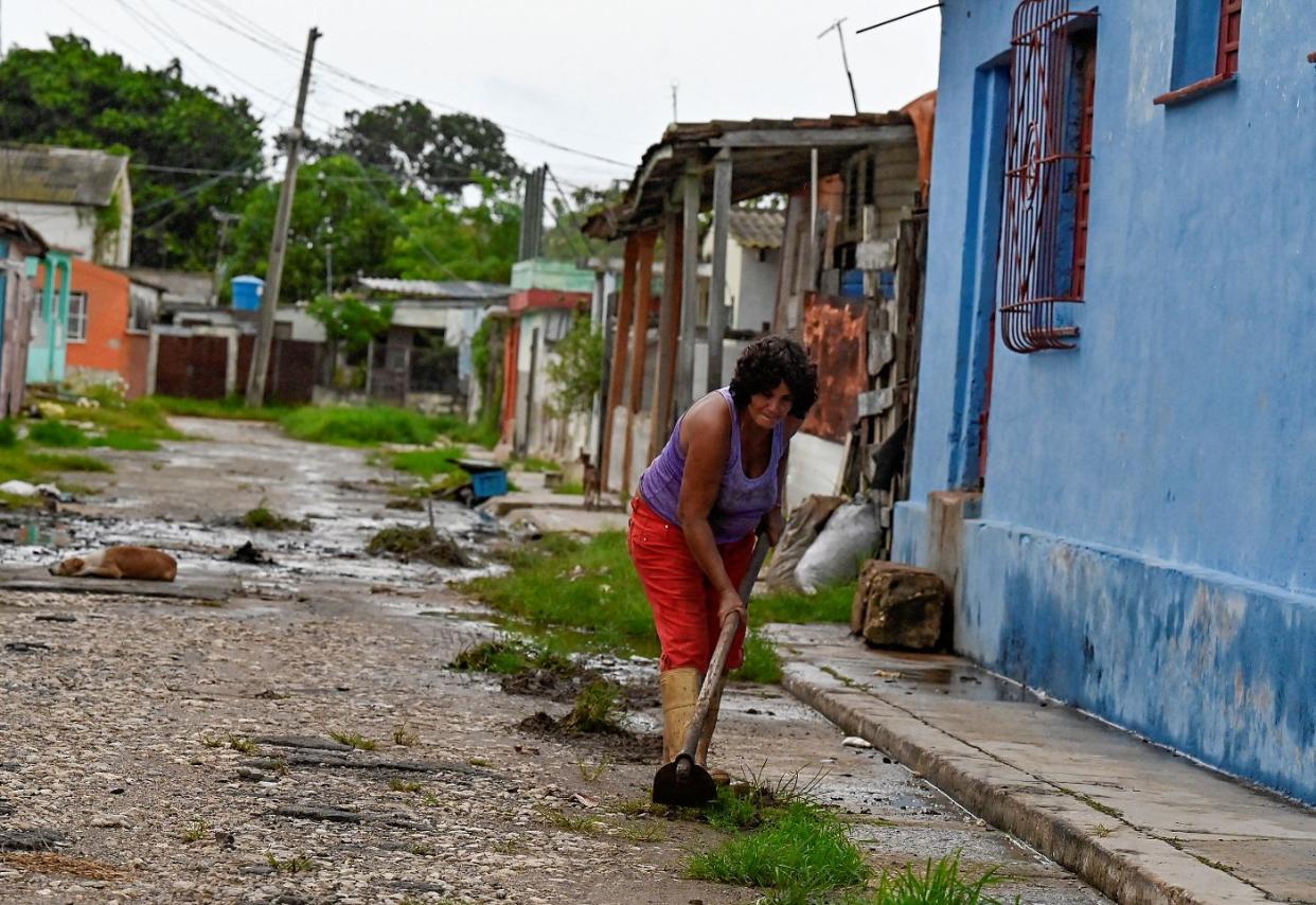 A woman cleans a drain near her home in Batabano, Mayabeque province, on Sept. 26, 2022, ahead of the arrival of Hurricane Ian in Cuba.