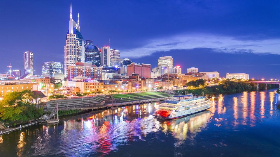 Nashville, Tennessee, USA skyline and riverboat on the Cumberland River at night.