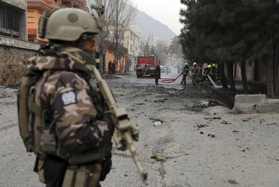 A soldier stands guard as firefighters work at the site of a bomb attack in Kabul, Afghanistan, Saturday, Feb. 20, 2021. Three separate explosions in the capital Kabul on Saturday killed and wounded numerous people an Afghan official said. (AP Photo/Rahmat Gul)