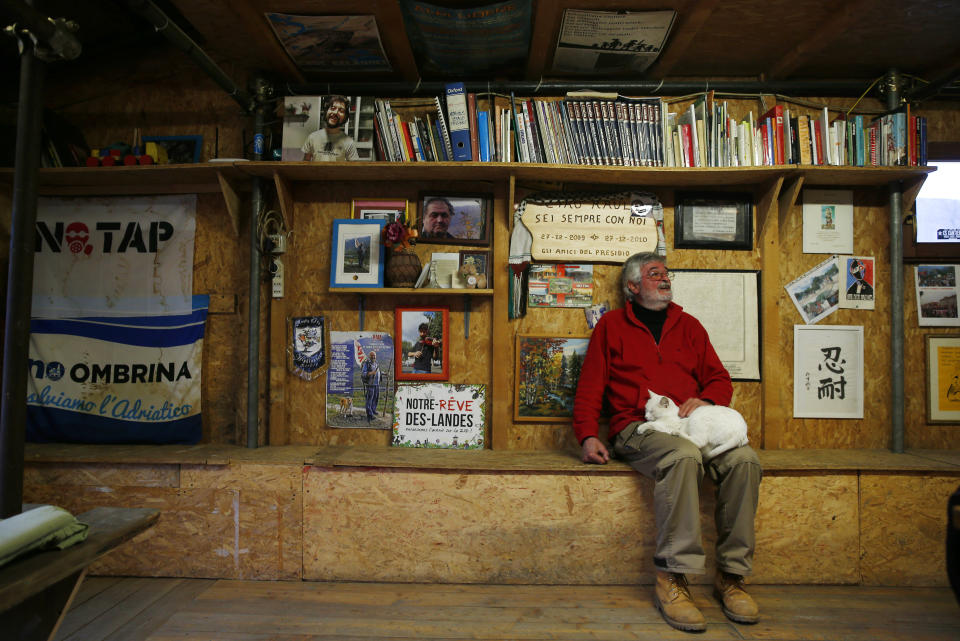 Guido Fissore, activist of the No-TAV movement, sits with his cat at the movement's headquarters in Venaus, northern Italy, Tuesday, Feb. 12, 2019. The TAV project is part of a European wide network to improve high-speed rail connections. On the Italian side, the construction site long targeted by sabotaging protesters is guarded by four law enforcement agencies and has been reduced to maintenance work only. The survival of Italy's increasingly uneasy populist government could very well depend on whether Italy restarts construction on the TAV link, which it halted in June.(AP Photo/Antonio Calanni)