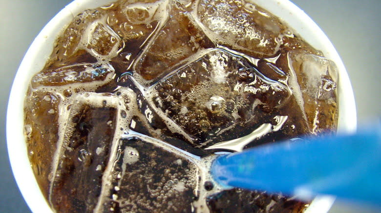 Cola in cup with ice and straw up close from above