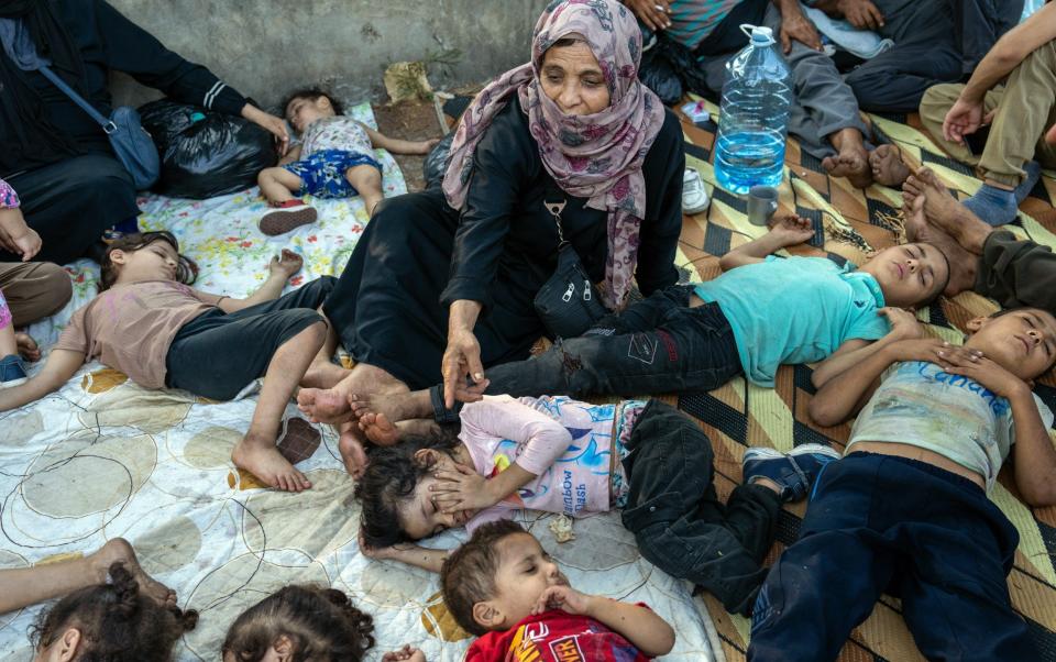 A woman watches over sleeping children at an outside shelter after being displaced by Israeli airstrikes in Beirut