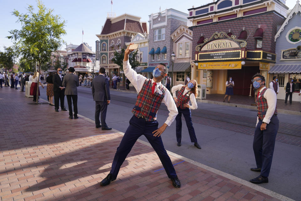 Employees take a photo on Main Street before the gates open at Disneyland in Anaheim, Calif., Friday, April 30, 2021. The iconic theme park in Southern California that was closed under the state's strict virus rules swung open its gates Friday and some visitors came in cheering and screaming with happiness. (AP Photo/Jae Hong)