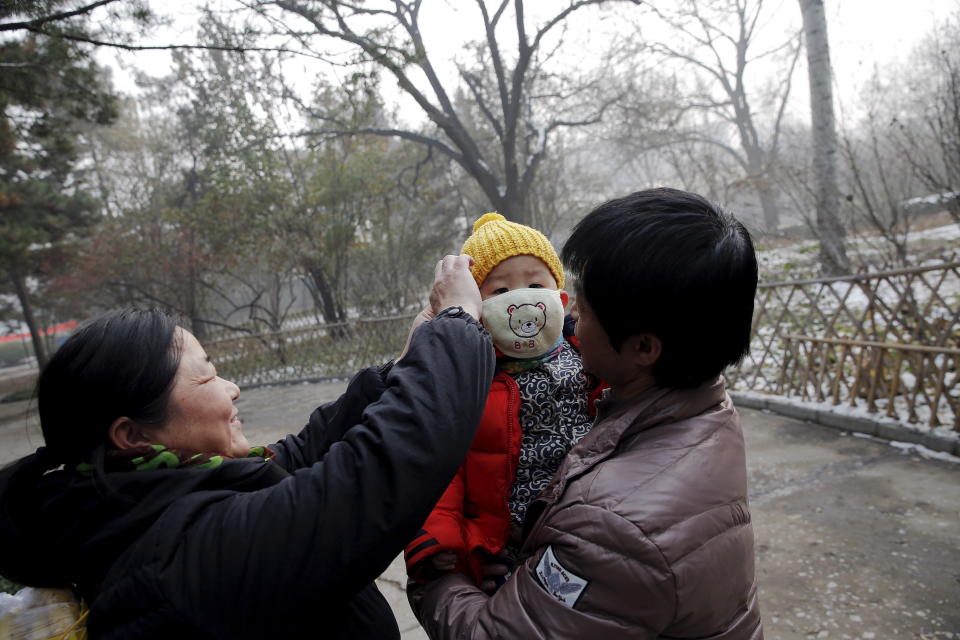 A woman fixes a protective mask on a baby during an extremely polluted day in Baoding, China.