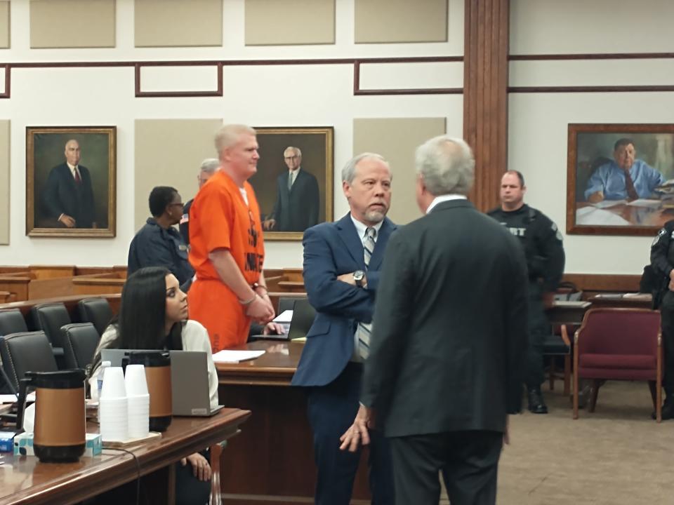 Alex Murdaugh, in an orange prison jumpsuit, stands in the Beaufort County courtroom Friday while state prosecutor Creighton Waters, center, and Murdaugh attorney Richard Harpootlian chat in the foreground.