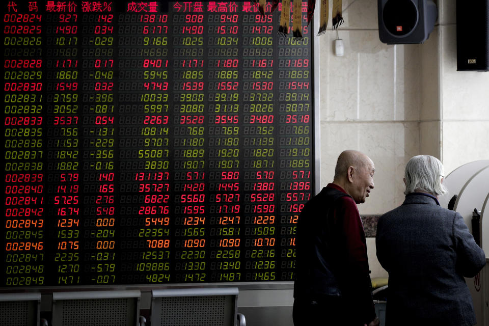 Investors chat near an electronic board displaying stock prices at a brokerage house in Beijing, Friday, Jan. 18, 2019. Chinese stocks rose Friday on signs of possible progress in negotiations over Beijing's tariff war with Washington. (AP Photo/Andy Wong)