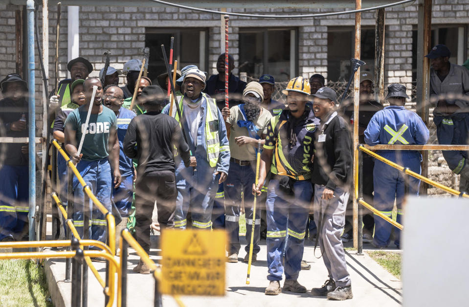 Mineworkers at the entrance of a goldmine in Springs, near Johannesburg, South Africa, Wednesday, Oct. 25, 2025. A company official says more than 100 miners have escaped from the mine after being held underground for three days by fellow employees in a union dispute. (AP Photo)