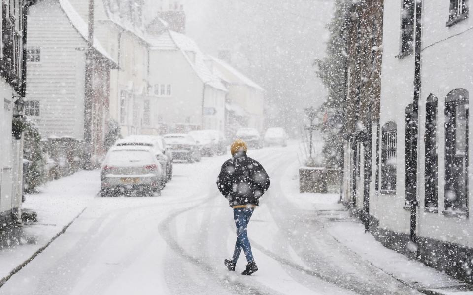 A person walking through a snow flurry in Lenham, Kent