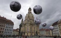 People watch balloons made by the 'ONE' campaigning organisation depicting leaders of the countries members of the G7 in front of the Frauenkirche cathedral in Dresden, Germany, May 27, 2015. REUTERS/Fabrizio Bensch