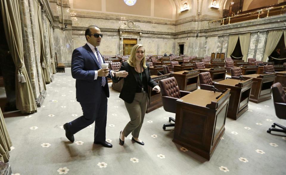 Washington Lt. Gov.-elect Cyrus Habib, left, carries coffee as he walks with his staff member Libby Hollingshead, Director of Operations and Legislative Liaison, in the Senate chamber, Thursday, Jan. 5, 2017, in Olympia, Wash. Habib will be Washington's first blind lieutenant governor, and the Senate has undergone a makeover that incorporates Braille into that chamber's floor sessions that will allow Habib to know by the touch of his finger which lawmaker is seeking to be recognized to speak. Habib is replacing Lt. Gov. Brad Owen, who is retiring. (AP Photo/Ted S. Warren)