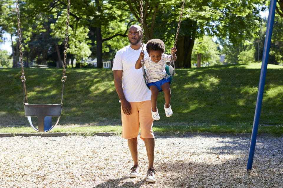 Royal Harris, pushes his grandson, Carter, 2, on swings at Woodlawn Park in Portland, Ore., Wednesday, July 20, 2022. Harris, who has lost friends and family to Portland's gang violence, says he supports diverting resources from cold case units to address spiking gun violence in the city. "If the case has been cold for five years and you've got a case that's two days old, which do you have the biggest capacity to find the answer for? I'm going to go with the new (one)," Harris says. (AP Photo/Craig Mitchelldyer)