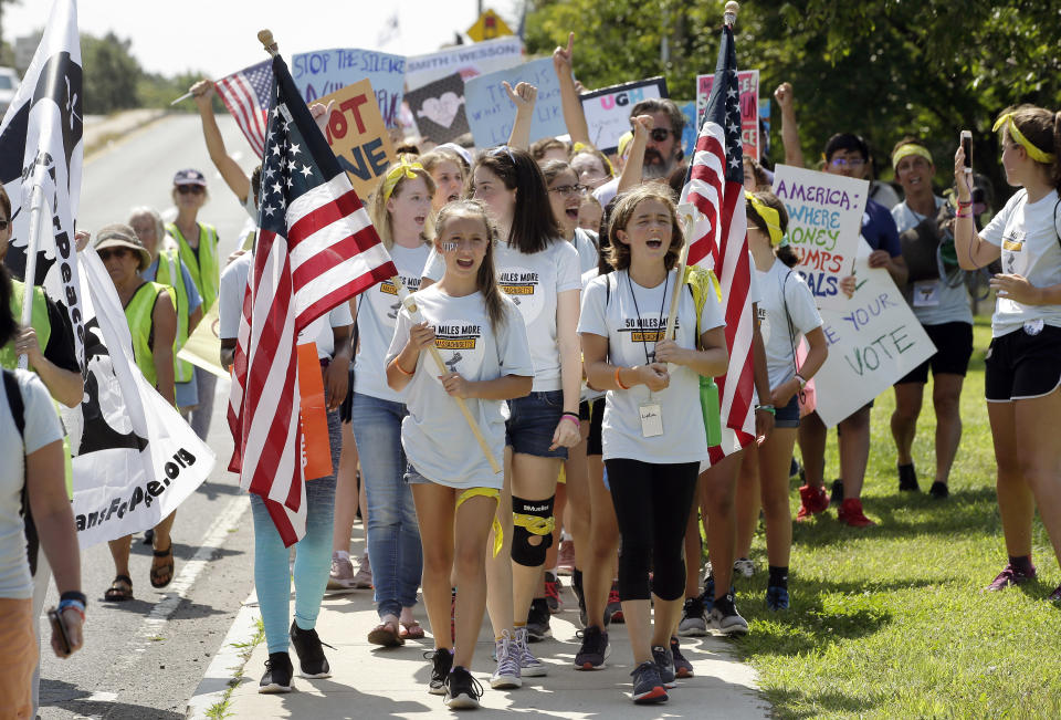 Demonstrators carry American flags and placards during the final mile of a 50-mile march, Sunday, Aug. 26, 2018, in Springfield, Mass. The march, held to call for gun law reforms, began Thursday, Aug. 23, 2018, in Worcester, Mass., and ended Sunday, in Springfield, with a rally near the headquarters of gun manufacturer Smith & Wesson. (AP Photo/Steven Senne)