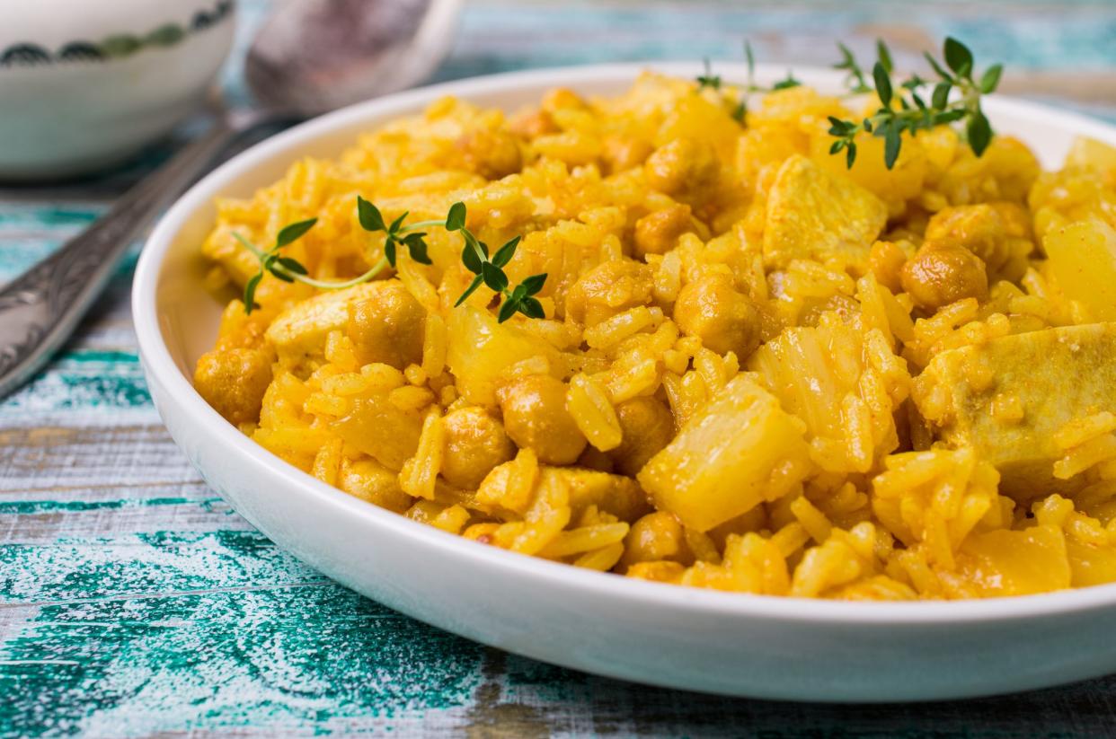 Traditional spicy rice with chicken and chickpeas on wooden background. Selective focus.