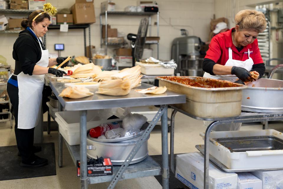 Patricia Nora, an employee at Food City Supermarket in El Paso spreads masa on the corn husk for the tamales while Nilfa Farfan arranges the tamales in a pot before they are steamed on Tuesday, Dec. 19, 2023.