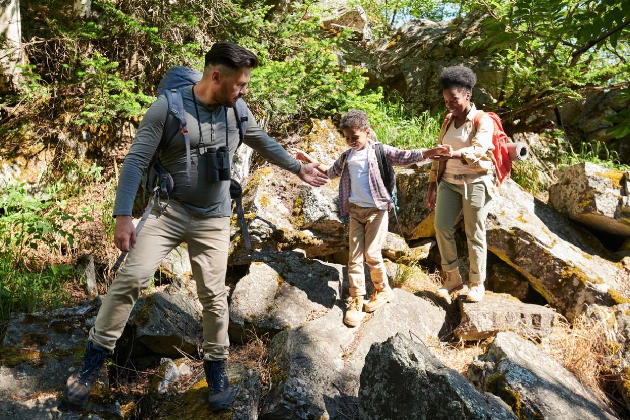 Family of three walking on big rocks they travelling in the wild nature