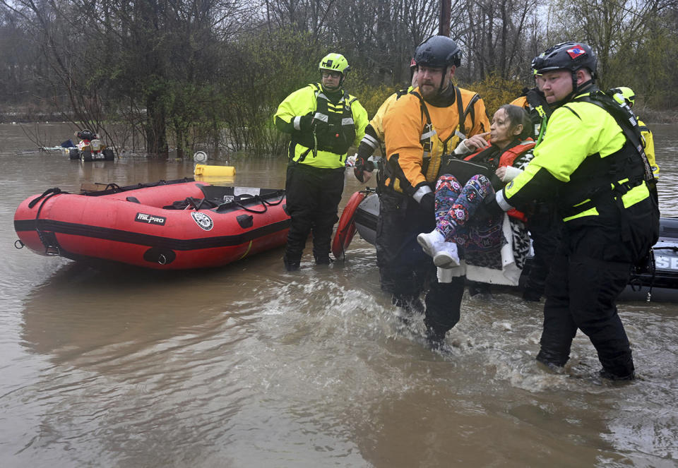 Beaver Falls, Pa., firefighter Jason Tyger, right, gets some help carrying a woman from a boat after she was rescued from her flooded home in Franklin Township, Pa., on April 3, 2024.  (Lucy Schaly / Pittsburgh Post-Gazette via AP)