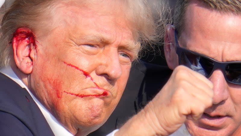 Republican presidential candidate former President Donald Trump gestures while surrounded by U.S. Secret Service agents as he is helped off the stage at a campaign rally in Butler, Pa., Saturday, July 13, 2024.