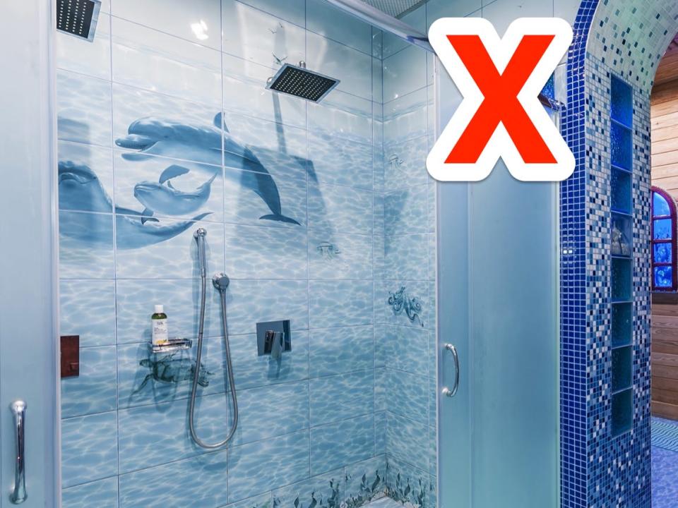 red x over a blue tiled bathroom with dolphin imagery on the shower wall