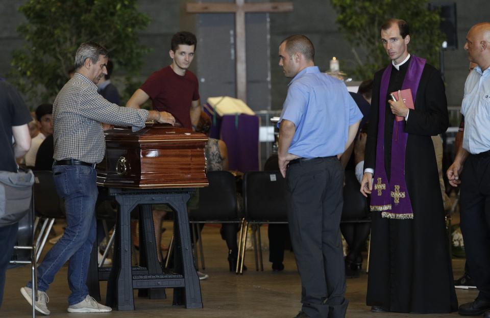 A man touches the coffin of one of the victims of the Morandi highway bridge collapse, in Genoa, Italy, Friday, Aug. 17, 2018. Officials say 38 people are confirmed killed and 15 injured. Prosecutors say 10 to 20 people might be unaccounted-for and the death toll is expected to rise. (AP Photo/Gregorio Borgia)
