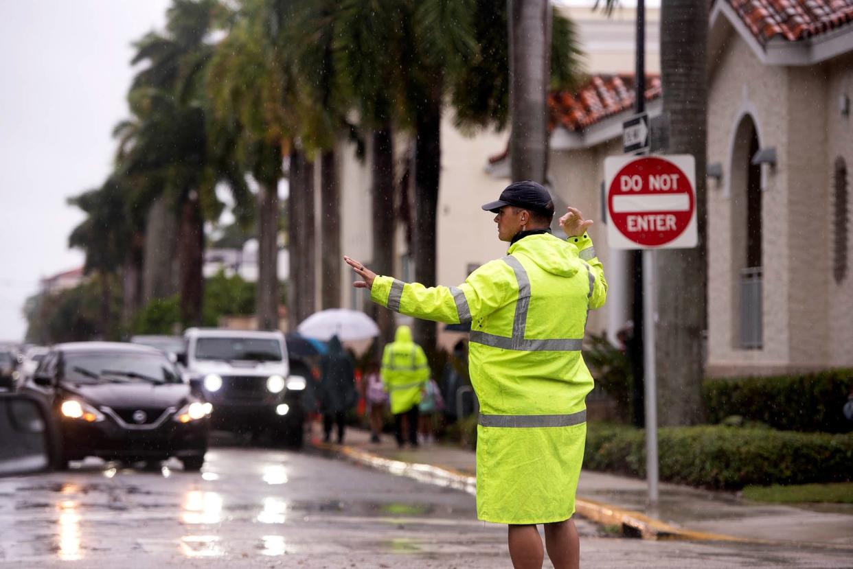 Palm Beach police officer Anthony DeJesse directs traffic Tuesday as Palm Beach Public School releases students before Hurricane Ian comes ashore in Florida.