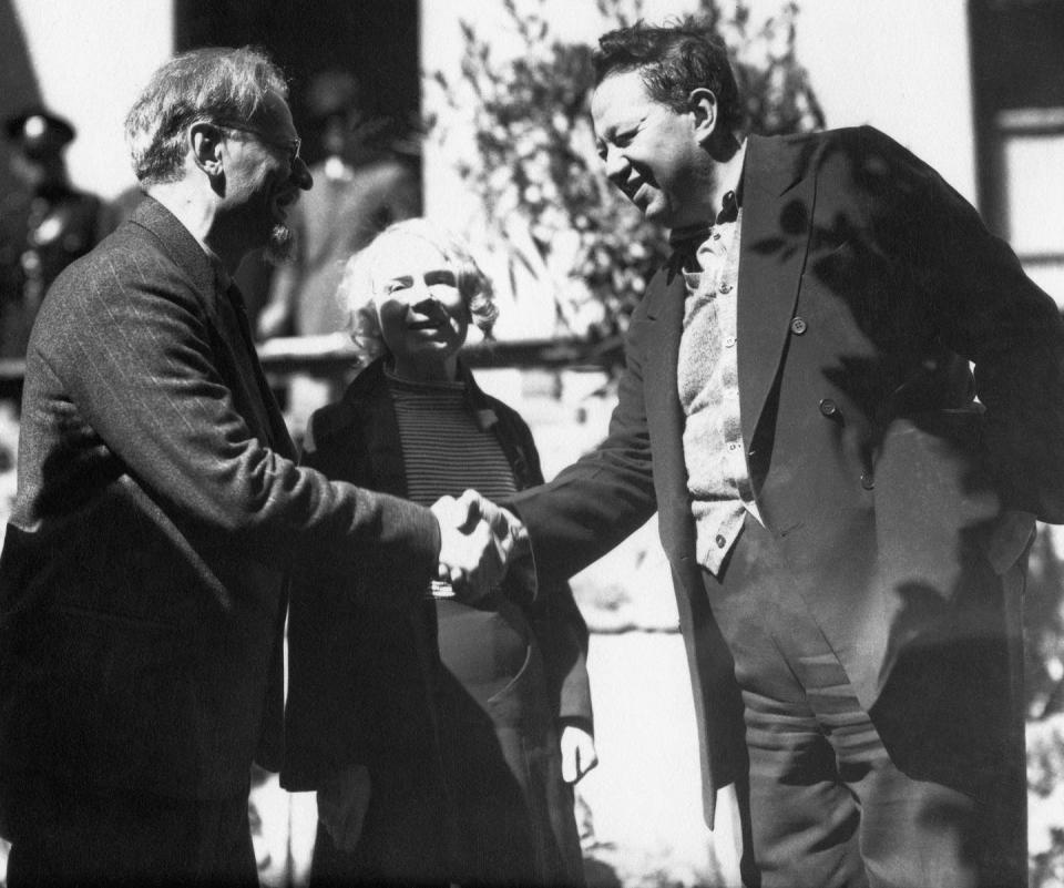 Imagen en blanco y negro de Trotsky y Diego Rivera dándose la mano, con una Sedova sonriente a su lado