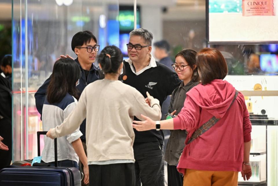 Passengers of Singapore Airlines flight SQ321, which made an emergency landing in Bangkok on its flight from London to Singapore, greet family members upon arrival at Changi Airport in Singapore, 22 May 2024 (EPA)
