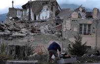 A man helps a woman in front of a collapsed building following an earthquake in Amatrice, central Italy, August 24, 2016. REUTERS/Emiliano Grillotti