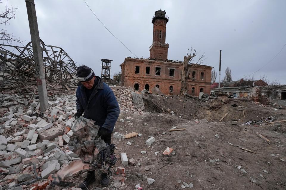 A man holds fragments of a rocket launched by Russian forces, a rocket crater behind him, in Kharkiv, Ukraine, on March 27, 2022.