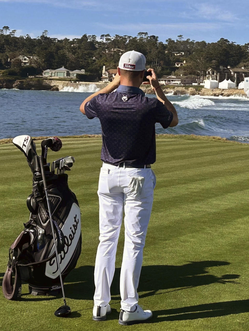 Justin Thomas stops to take a photo of the 18th hole at Pebble Beach on Monday, Jan. 29, 2024, during the AT&T Pebble Beach Pro-Am in Pebble Beach, Calif. Good weather was expected to give way to rain for the PGA Tour's signature event. (AP Photo/Doug Ferguson)