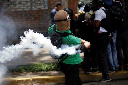 A demonstrator throws a tear gas canister during the 'march of the empty pots' against Venezuelan President Nicolas Maduro's government in Caracas, Venezuela, June 3, 2017. REUTERS/Marco Bello