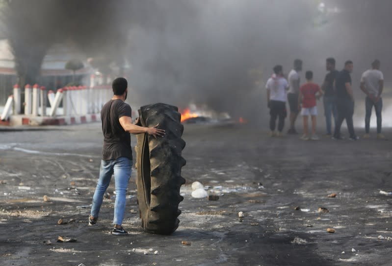 A demonstrator holds a tire during a protest targeting the government over an economic crisis, in Nabatiyeh