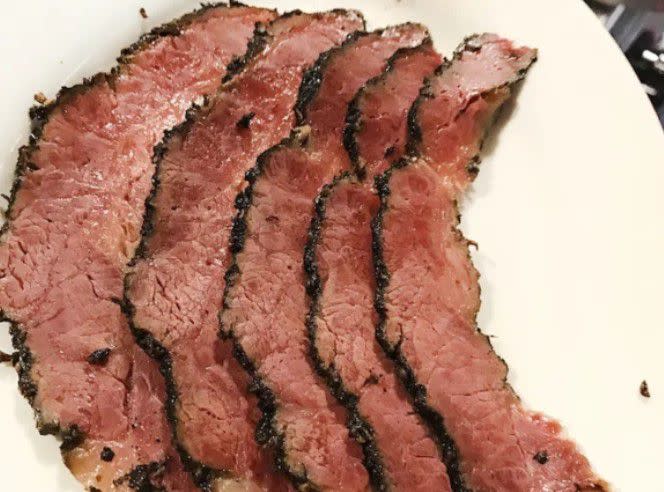 <p><a href="https://www.goldbelly.com/foods/pastrami?utm_source=blog&utm_medium=pastrami+vs+corned+beef&utm_campaign=pastrami" rel="nofollow noopener" target="_blank" data-ylk="slk:Pastrami;elm:context_link;itc:0;sec:content-canvas" class="link rapid-noclick-resp">Pastrami</a> is a deli meat made from beef that is brined and smoked. Brisket is traditionally made from a cut called the navel, located below the ribs, but it’s also frequently made from the brisket, which itself is comprised of the fattier “point” (also called deckle) and the leaner “flat” (also called “first cut”). </p><p><br></p><p>To make pastrami, the brisket is brined. It is then seasoned with herbs and spices like salt, coriander, mustard seeds, and black pepper. It is then smoked and steamed, yielding juicy and tasty meat. </p><p><br></p><p>Pastrami can trace its roots to Eastern Europe, specifically Romania. It gets its name from <em>pastirma</em>, an air-dried cured and seasoned beef that is popular in Europe and the Middle East. Pastrami is sliced and often served piled high in sandwiches.</p><span class="copyright"> Liebman’s Deli </span>