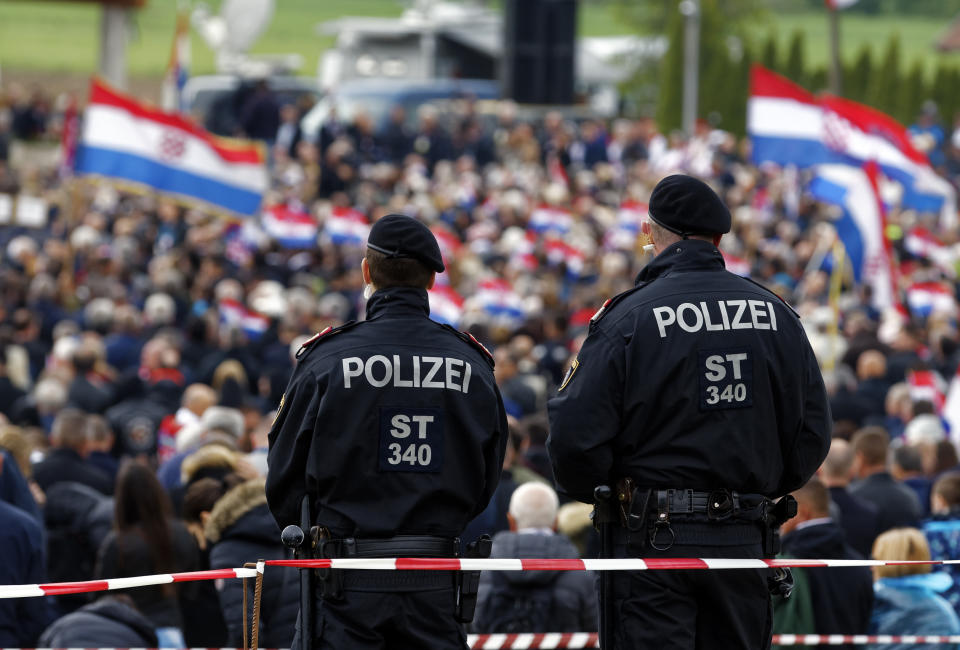 Austrian police officers observe as thousands of mourners gather for a liturgical service in Bleiburg, Austria, Saturday, May 18, 2019. Thousands of Croatian far-right supporters have gathered in a field in southern Austria to commemorate the massacre of pro-Nazi Croats by communists at the end of World War II. (AP Photo/Darko Bandic)