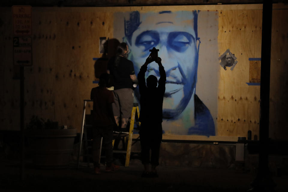 An artist creates an image of George Floyd on Thursday, May 28, 2020, in Minneapolis. Violent protests over the death of Floyd, the black man who died in police custody, broke out in Minneapolis for a third straight night. (AP Photo/Julio Cortez)