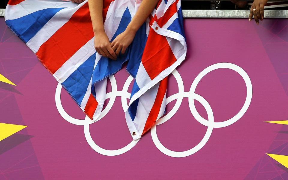 A cycling fan holds a British flag over the Olympic Rings logo during the men's Road Cycling Race at the London 2012 Olympic Games - Shutterstock 