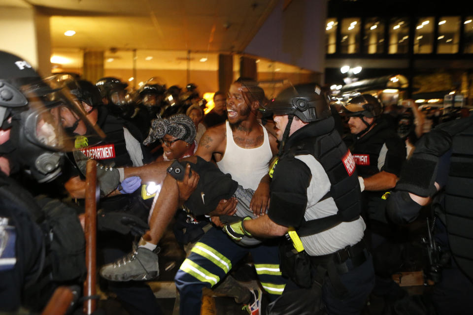 Police and demonstrators&nbsp;carry a seriously wounded individual&nbsp;into the parking area of the the Omni Hotel during a march to protest the death of Keith Scott.