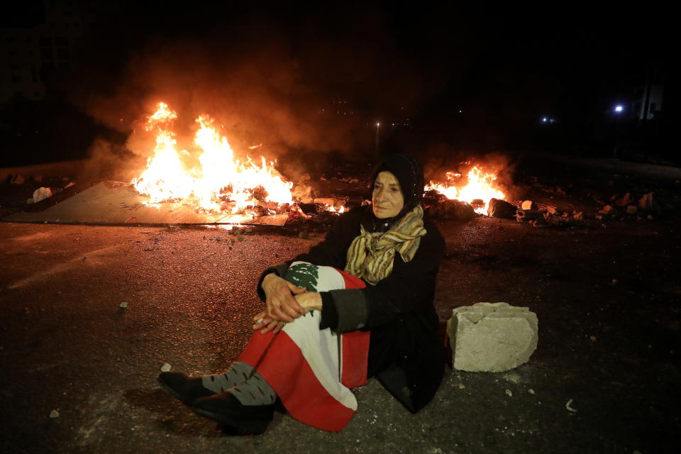 黎巴嫩經濟危機引發民眾不滿，紛紛焚燒輪胎、物品等示威。一名示威者在大火旁靜坐抗議。圖片來源：Reuers。