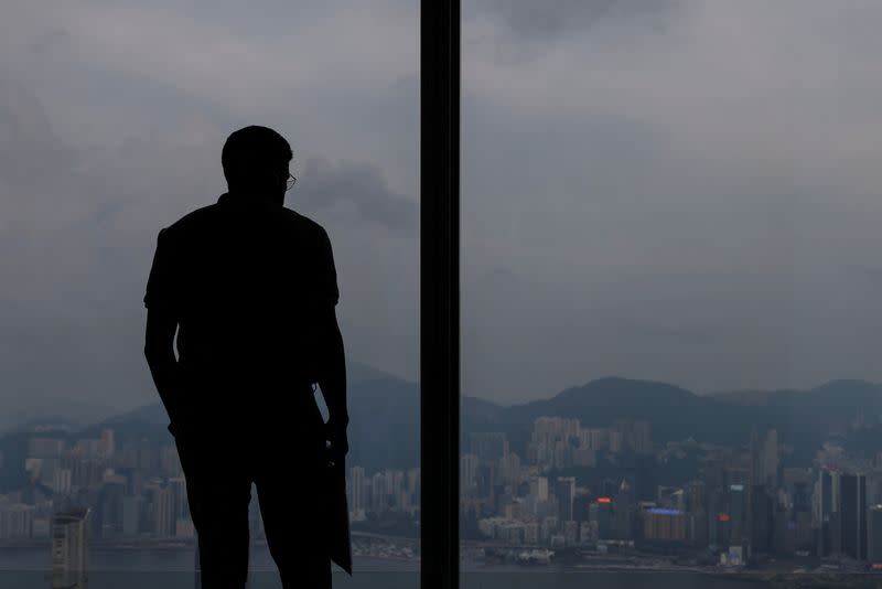 A man looks down at the scenic view of the city from an observation deck in Hong Kong