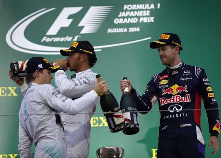 Mercedes Formula One driver Lewis Hamilton of Britain (C) celebrates with second-placed teammate Nico Rosberg of Germany and third-placed Red Bull Formula One driver Sebastian Vettel of Germany after winning the Japanese F1 Grand Prix at the Suzuka Circuit October 5, 2014. REUTERS/Toru Hanai
