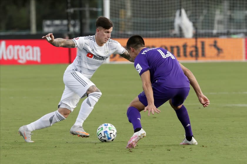 Los Angeles FC midfielder Brian Rodriguez, left, moves the ball past Orlando City defender Joao Moutinho (4) during the first half of an MLS soccer match, Friday, July 31, 2020, in Orlando, Fla. (AP Photo/John Raoux)