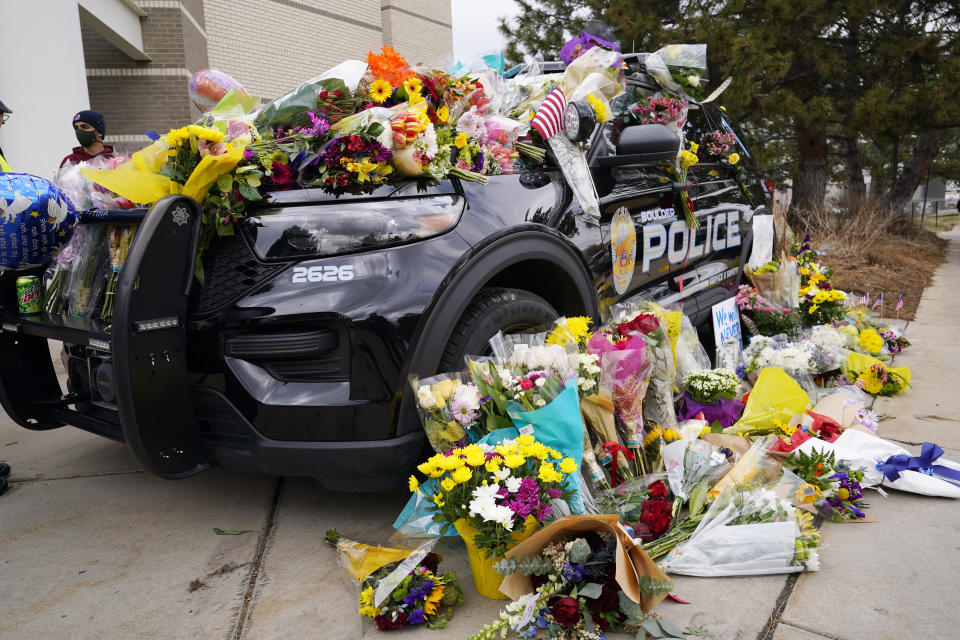 Police cruiser parked outside Boulder Police Department is covered with bouquets in tribute after an officer was one of the victims of a mass shooting at a King Soopers grocery store Tuesday, March 23, 2021, in Boulder, Colo. (AP Photo/David Zalubowski)