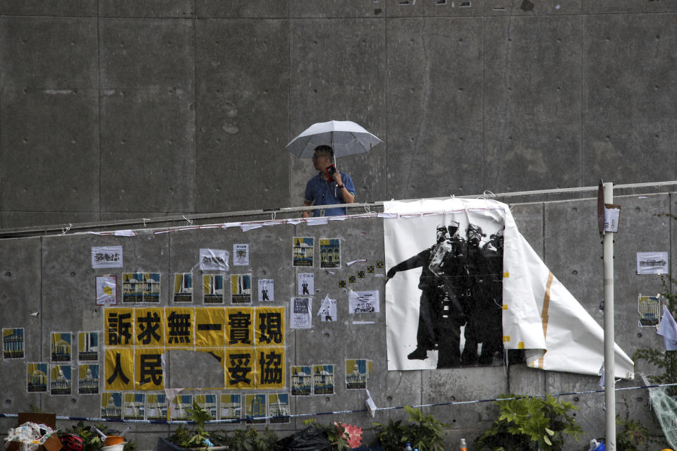 A man carries an umbrella in the rain as he passes posters and banners placed by protesters on the wall outside the Legislative Council building in Hong Kong, Wednesday, July 3, 2019. A pro-democracy lawmaker who tried to stop Hong Kong protesters from breaking into the legislature this week says China will likely use the vandalizing of the building as a reason to step up pressure on the Chinese territory. (AP Photo/Andy Wong)