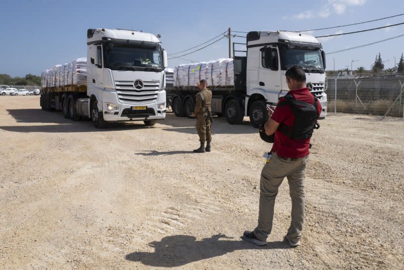 An Israeli soldier (L) and a security guard keep track of trucks of humanitarian aid arriving from the Ashdod port to the Erez Crossing checkpoint before entering to the northern Gaza Strip on Sunday. Photo by Jim Hollander/UPI