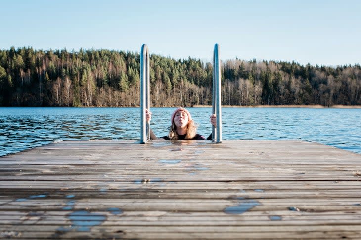 woman in cold water up to her shoulders, wearing beanie