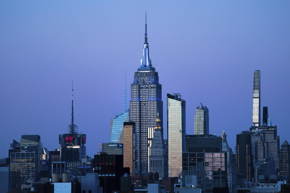 FILE - The Empire State Building glows blue during dusk, Monday, Nov. 14, 2022, in New York. Around Manhattan and elsewhere in the city, hotels that served tourists just a few years ago have become de facto emergency shelters. The latest is the historic Roosevelt Hotel in midtown Manhattan, which shuttered three years ago, is reopening later this week as a welcome center and shelter for asylum seekers. (AP Photo/Julia Nikhinson, File)