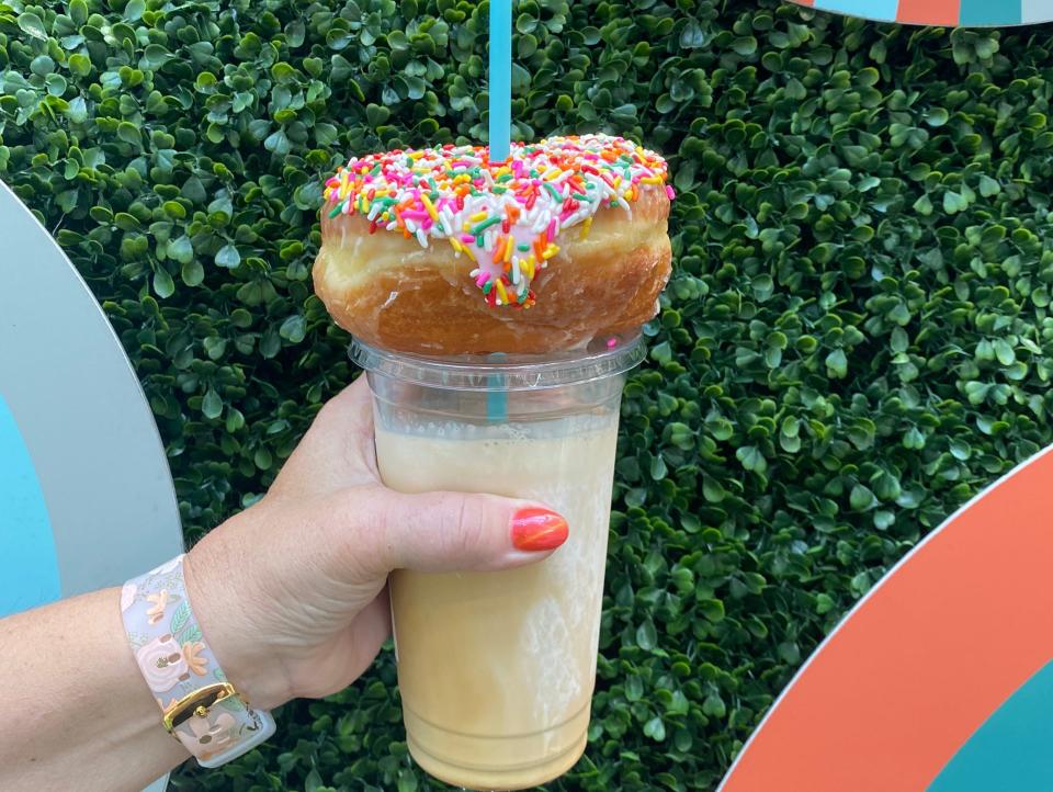 hand holding coffee with doughnut on the straw at everglazed in disney springs