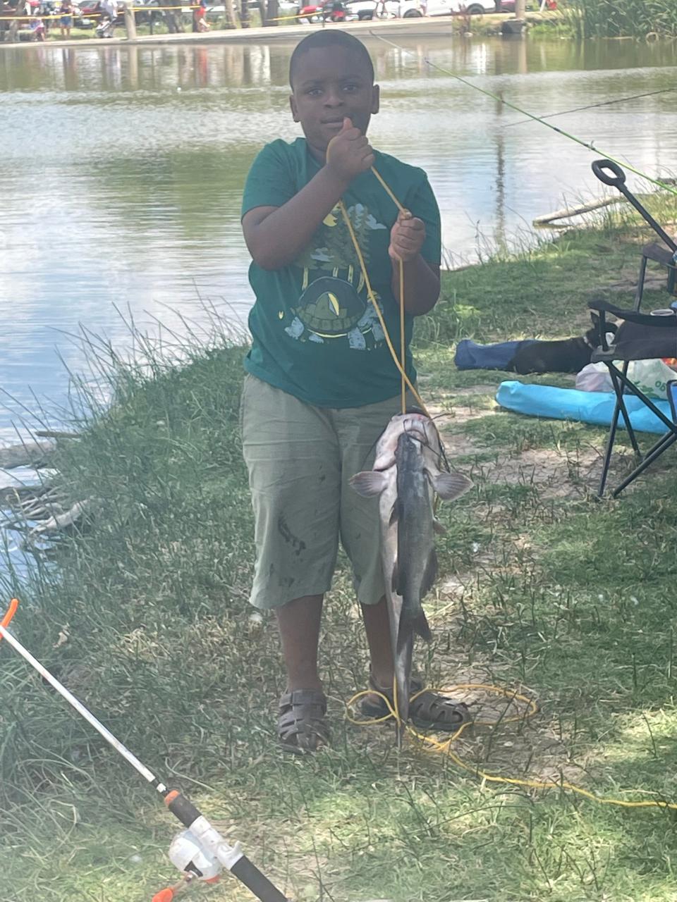 Brayden Johnson shows off the catfish he caught during the annual fishing tournament