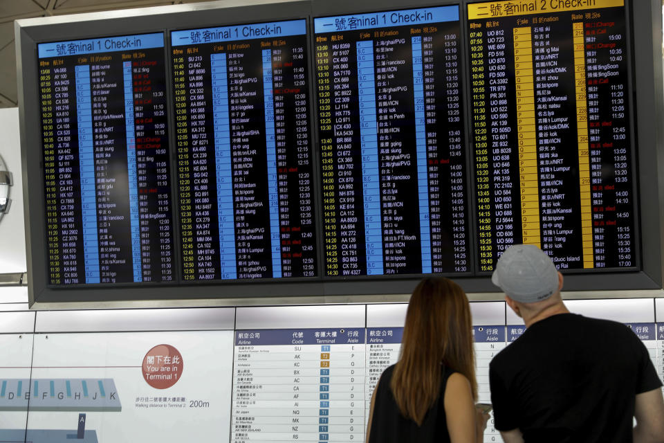 Travellers check on information of their flight at the airport in Hong Kong, Wednesday, Aug. 14, 2019. Flight operations resumed at the airport Wednesday morning after two days of disruptions marked by outbursts of violence highlighting the hardening positions of pro-democracy protesters and the authorities in the Chinese city that's a major international travel hub. (AP Photo/Vincent Thian)